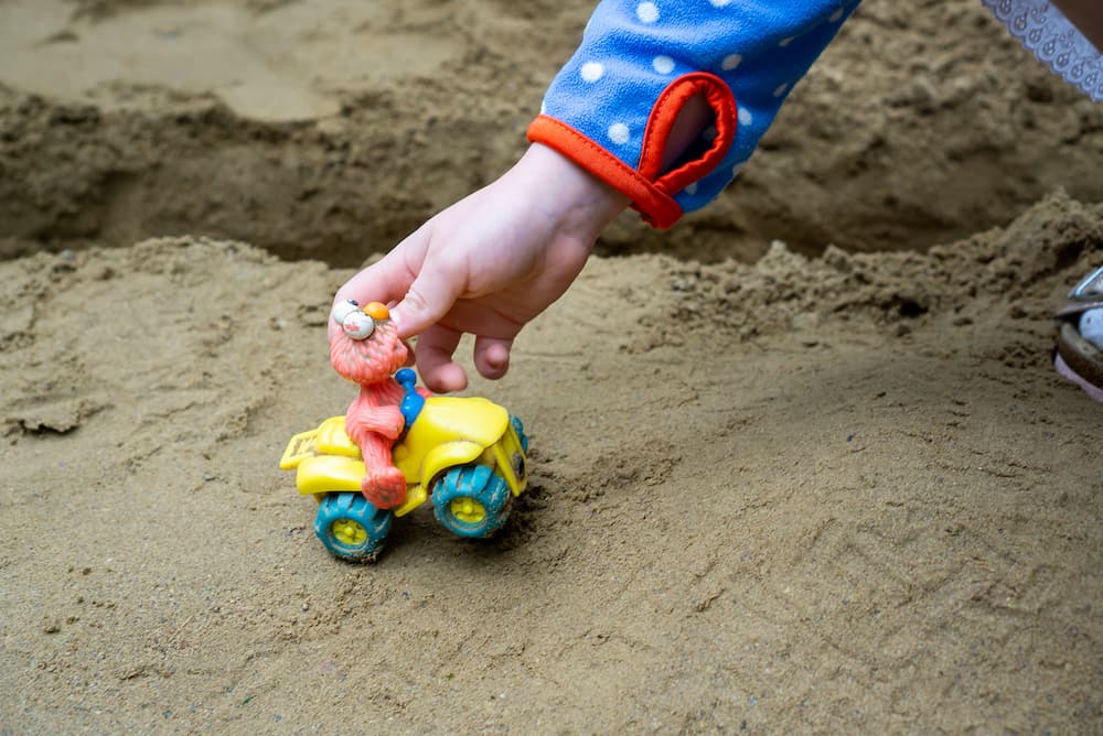 kind_spielt_mit_auto_im_sand-kita-dorothea-erxleben